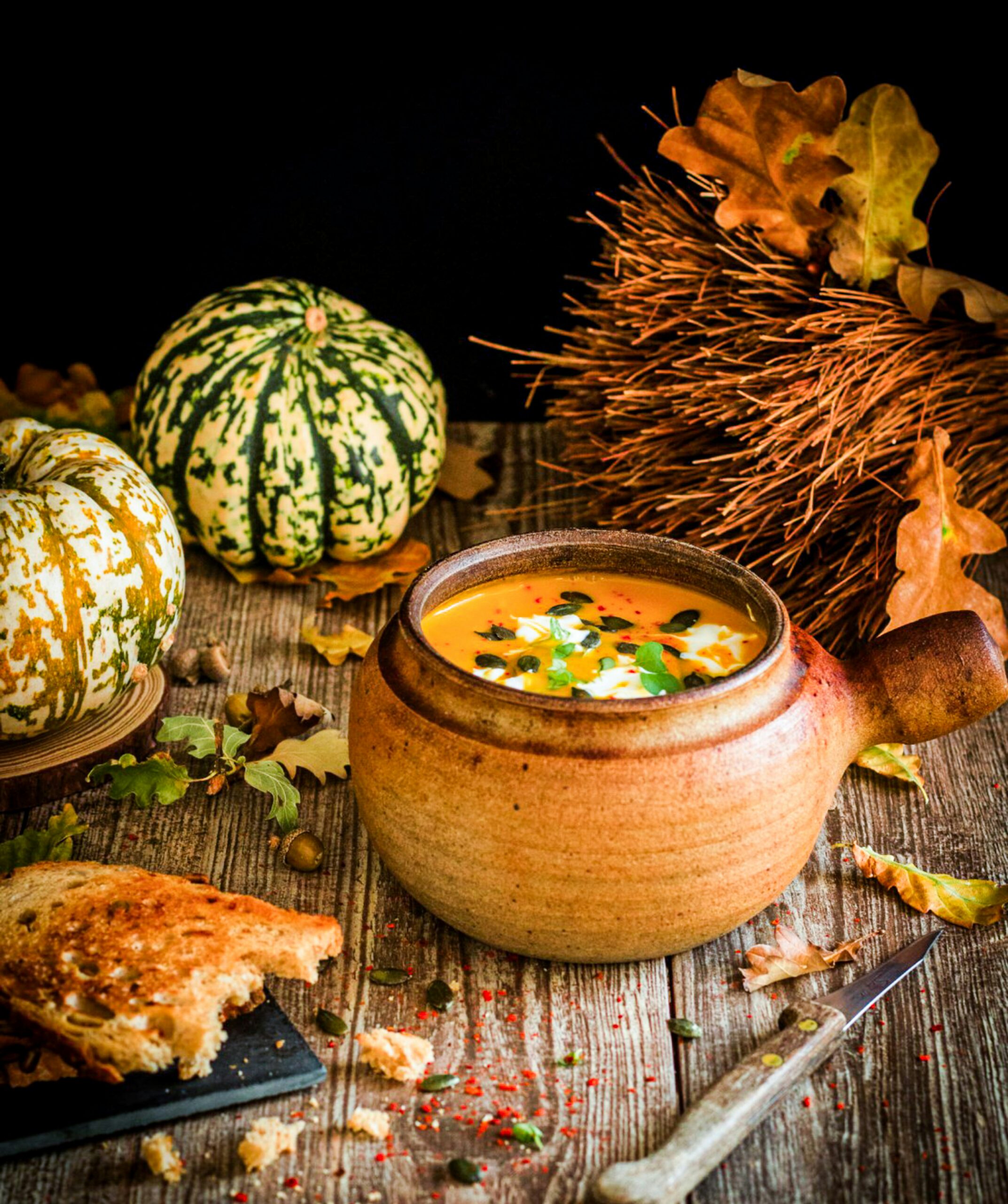 Herbstgerichte für die Familie — cremige Kürbissuppe im Teller mit knusprigen Croutons daneben
